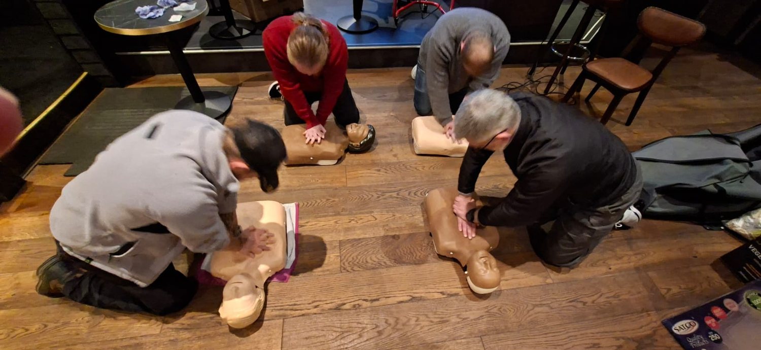 Three delegates practising chest compressions on adult CPR manikins