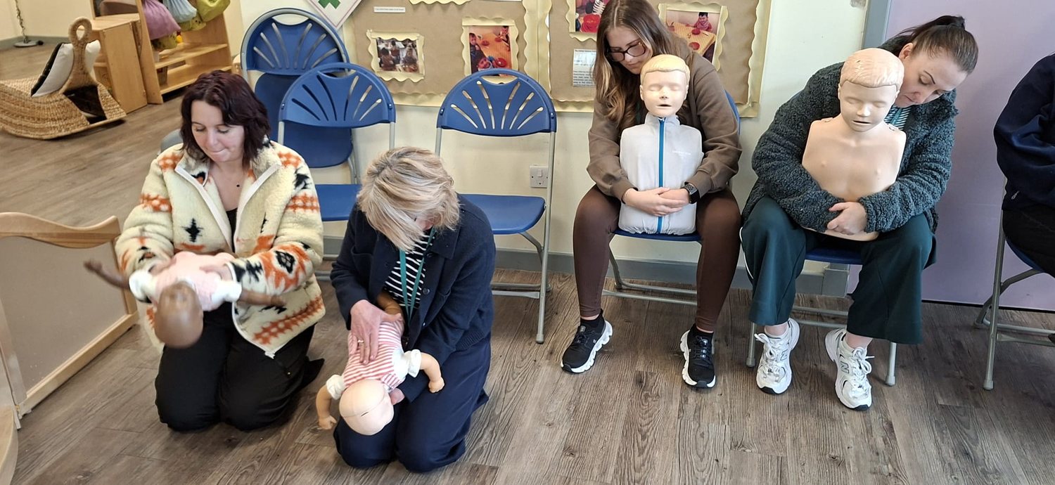 Nursery staff practising with infant and child manikins on a paediatric first aid course