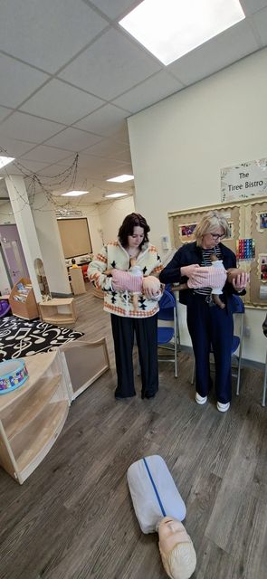 Two nursery staff holding infant manikins during a paediatric first aid course
