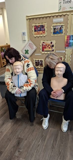 Two delegates practising back blows on child manikins seated on their laps