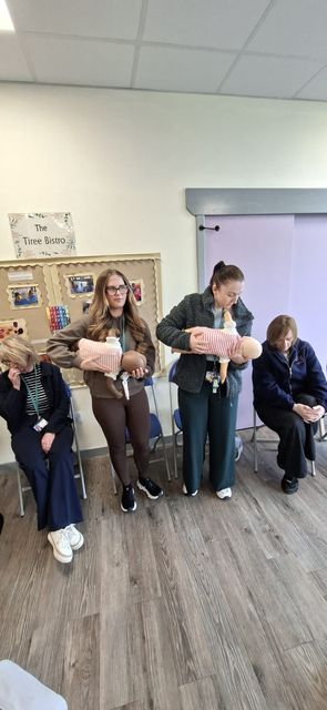 Nursery staff holding infant manikins during a paediatric first aid session