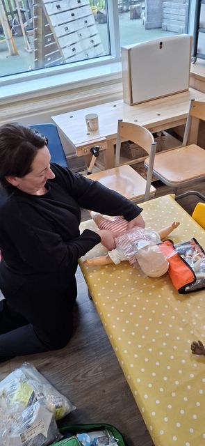 The trainer setting up an infant manikin and first aid kit for a practical exercise