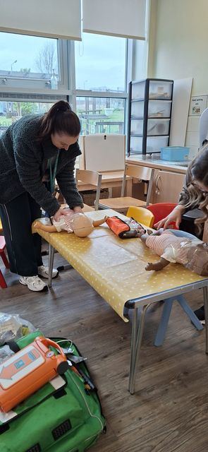 A delegate practising infant first aid with an AED and response bag alongside