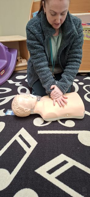 A delegate practising chest compressions on a child manikin in a nursery room