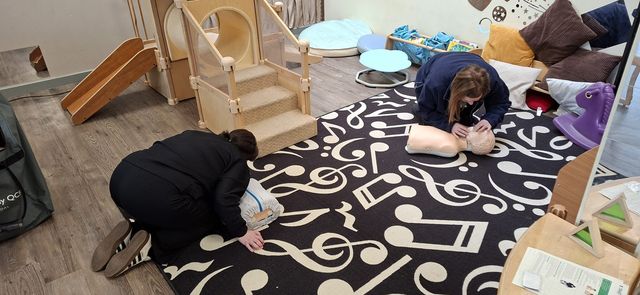 Two delegates practising CPR on child manikins in a nursery playroom